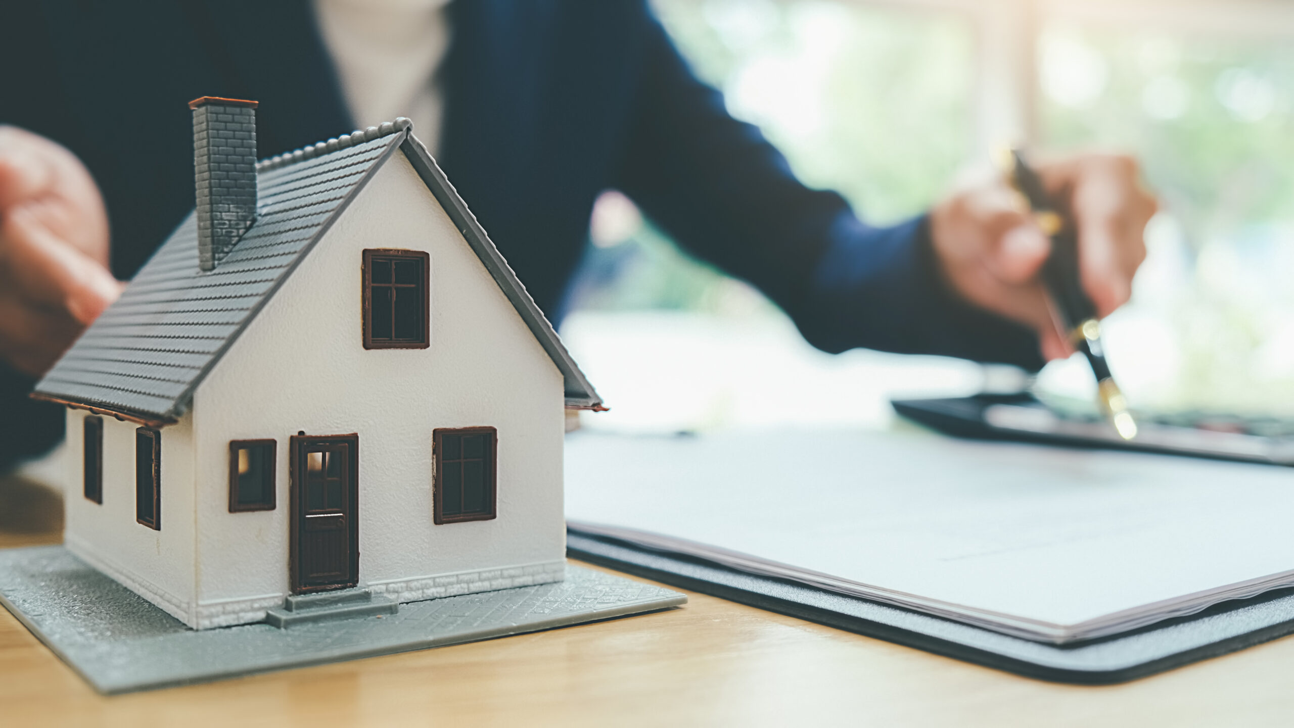 Immobilienmakler mit Hausmodell bei der Beratung